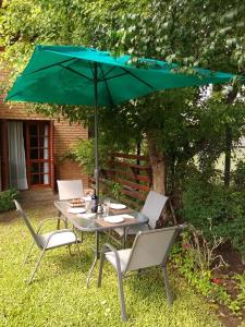 une table et des chaises avec un parasol vert dans l'établissement RIO y VERDE, à Córdoba