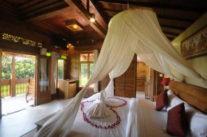 1 dormitorio con 1 cama blanca con dosel en Pondok Sebatu Eco Lodge, en Tegalalang