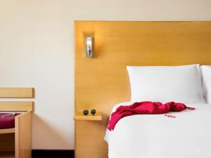 1 dormitorio con cama blanca y cabecero de madera en ibis Muscat, en Mascate