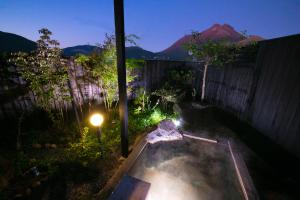 um quintal com uma banheira de hidromassagem no quintal à noite em Yufuin Bath Satoyamasafu em Yufu