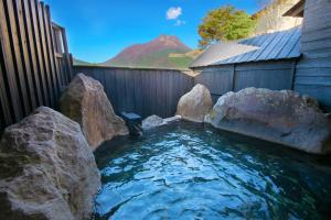 uma piscina de água com pedras num quintal em Yufuin Bath Satoyamasafu em Yufu