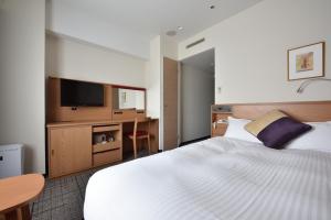 Dormitorio con cama, escritorio y TV en Hotel Granvia Hiroshima, en Hiroshima