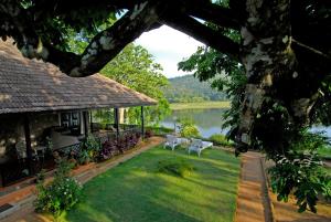 un patio con dos bancos y una casa con un lago en Lake Palace, en Thekkady