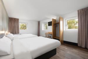 um quarto de hotel com duas camas e duas janelas em B&B HOTEL Lyon Centre Monplaisir em Lyon