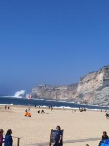 a group of people sitting on a beach at Casa da Leninha in Nazaré