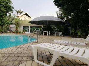 einen Pool mit zwei Stühlen und einem Sonnenschirm neben einem Tisch in der Unterkunft Terrace Hotel in Bandar Seri Begawan