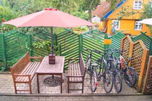 een tafel en stoelen met fietsen en een parasol bij Guest House Vasara in Nida