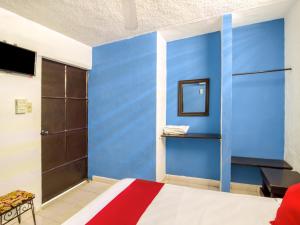 a room with a bed with a blue wall at Hotel Aventura in Mérida