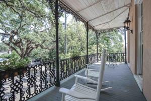 eine Veranda mit weißen Stühlen, Tischen und Bäumen in der Unterkunft Malaga Inn in Mobile