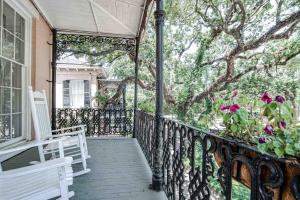 eine Veranda mit einer weißen Bank und einem Baum in der Unterkunft Malaga Inn in Mobile