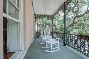 zwei weiße Stühle auf der Veranda eines Hauses in der Unterkunft Malaga Inn in Mobile