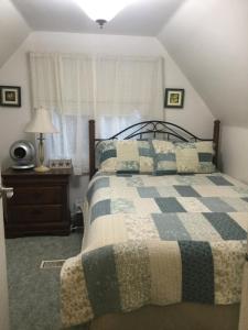 a bedroom with a bed with a blue and white quilt at Burley's Executive Garden Suite in Peterborough