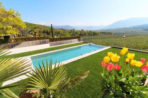 una piscina in mezzo a un cortile fiorito di Hotel Römerrast a Caldaro