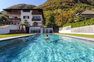 una donna in una piscina di fronte a una casa di Hotel Römerrast a Caldaro