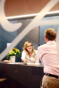 un homme et une femme devant un miroir dans l'établissement Ambassador Self Check-in Hotel, à Lucerne