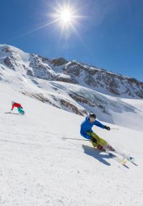 Duas pessoas estão a esquiar numa montanha coberta de neve. em Wellnesshotel Schweizerhof em Saas-Fee