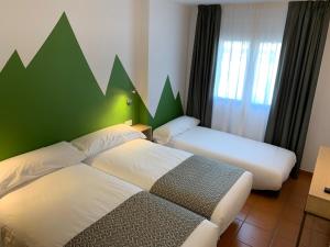 1 dormitorio con 2 camas y pared verde en Hotel Musher, en Pas de la Casa