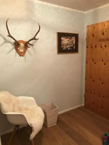 een kamer met een stoel en een gewei aan de muur bij Chalet Studio - Top Ausstattung - beste Lage Davos in Davos