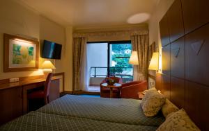 Habitación de hotel con cama, escritorio y ventana en Monte Mar Palace Hotel, en Ponta Delgada