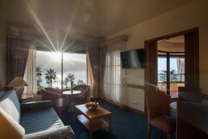 sala de estar con sofá, mesa y ventana en Monte Mar Palace Hotel, en Ponta Delgada