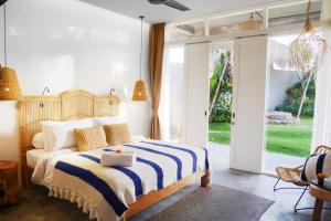 ein Schlafzimmer mit einem Bett mit einer blau-weißen gestreiften Decke in der Unterkunft Amar Boutique Hotel in Canggu