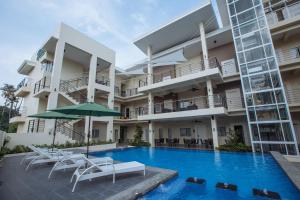 vistas a un edificio con piscina, sillas y sombrilla en Rovira Suites, en Dumaguete