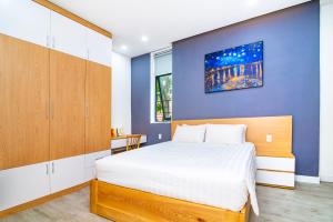 1 dormitorio con 1 cama grande y pared azul en An Homestay, en Da Nang