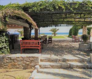 un banco rojo bajo una pérgola con vistas al océano en Ktima Petalea, en Gythio