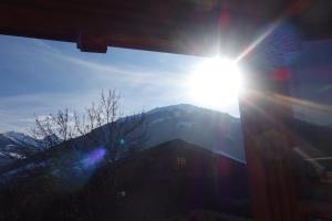 un sol brillando sobre un edificio con una montaña en el fondo en Haus Postfeld, en Alpbach