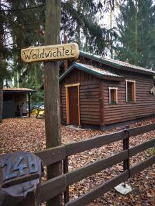 een bord op een hek voor een hut bij Holzhaus Waldwichtel am Wald und See in Neuruppin