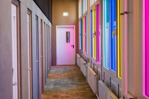 a hallway with a pink door and colorful windows at BoxHotel Hannover in Hannover