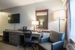 een hotelkamer met een bureau, een stoel en een spiegel bij Amsterdam Inn & Suites Moncton in Moncton