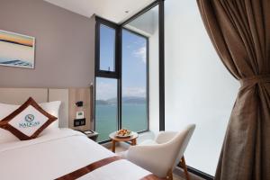 una camera d'albergo con un letto e una grande finestra di Nalicas Nha Trang Hotel a Nha Trang