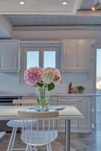 un jarrón de flores sentado en una mesa en una cocina en White Cliff Naousa, en Naousa