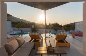 a patio with chairs and a table and a pool at PAROS ELITAS VILLAS in Parikia