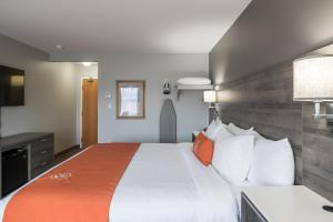 een slaapkamer met een groot bed met witte lakens en oranje kussens bij Amsterdam Inn & Suites Moncton in Moncton