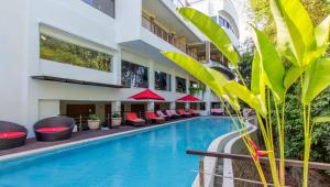 a hotel swimming pool with red chairs next to a building at Nunamkhalu Private Villa and Spa in Nusa Dua