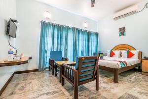 um quarto com uma cama, uma secretária e uma televisão em FabExpress Santhi Inn - Near Promenade Beach em Pondicherry