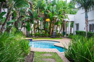 a swimming pool in front of a house with palm trees at Premier Hotel The Richards in Richards Bay