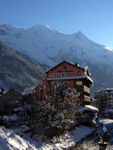 un edificio nella neve con una montagna sullo sfondo di Hôtel Vallée Blanche a Chamonix-Mont-Blanc