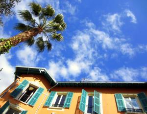 um edifício amarelo com janelas azuis e uma palmeira em Maison Durante em Nice