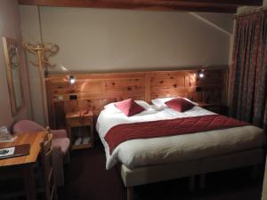 a bedroom with a large bed with red and white sheets at Hotel Le Clocher in Champoluc