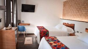 a hotel room with two beds and a television at Hotel Zamna Boutique in Mérida