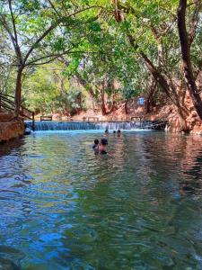 dos personas nadando en un río con una cascada en Prime Hotel Águas da Serra, en Rio Quente