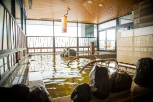 Habitación con piscina de agua en un edificio en La Vista Furano Hills Natural Hot Spring, en Furano