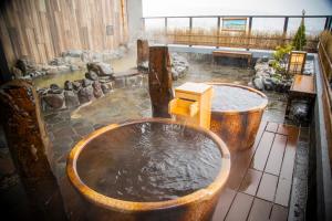 bañera llena de agua en una habitación en La Vista Furano Hills Natural Hot Spring, en Furano