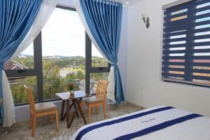 Schlafzimmer mit einem Bett, einem Tisch und einem Fenster in der Unterkunft Luan'S Villa in Da Lat