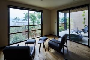 een kamer met stoelen, een tafel en grote ramen bij 宮島離れの宿 IBUKU 別邸 -Miyajima Hanarenoyado IBUKU Bettei- in Ōno