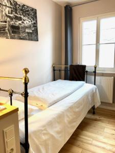 - une chambre avec un lit doté de draps blancs et d'une chaise dans l'établissement Hotel Alexander, à Wiesbaden