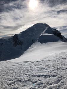 een berg bedekt met sneeuw met de zon erachter bij Hôtel Val d'Este in Saint-Gervais-les-Bains